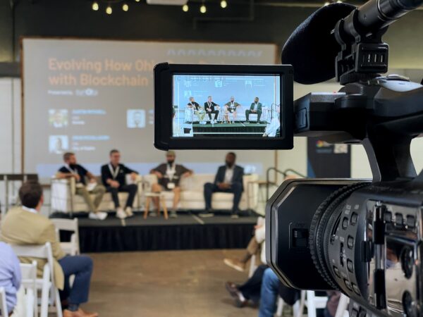 Video camera capturing panel of speakers at Amplify