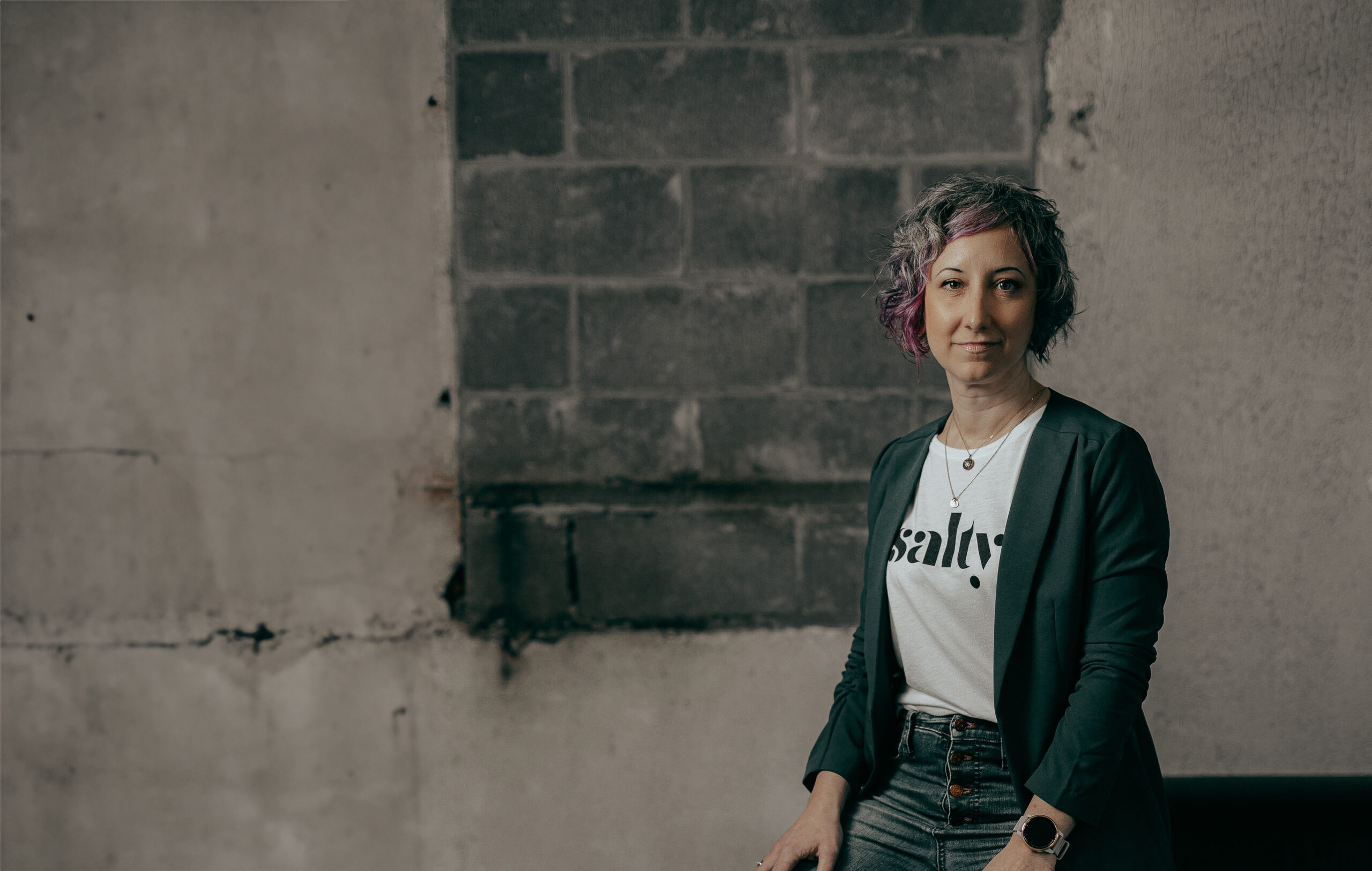 Jenna wearing a shirt that says Salty with a distressed wall in the background